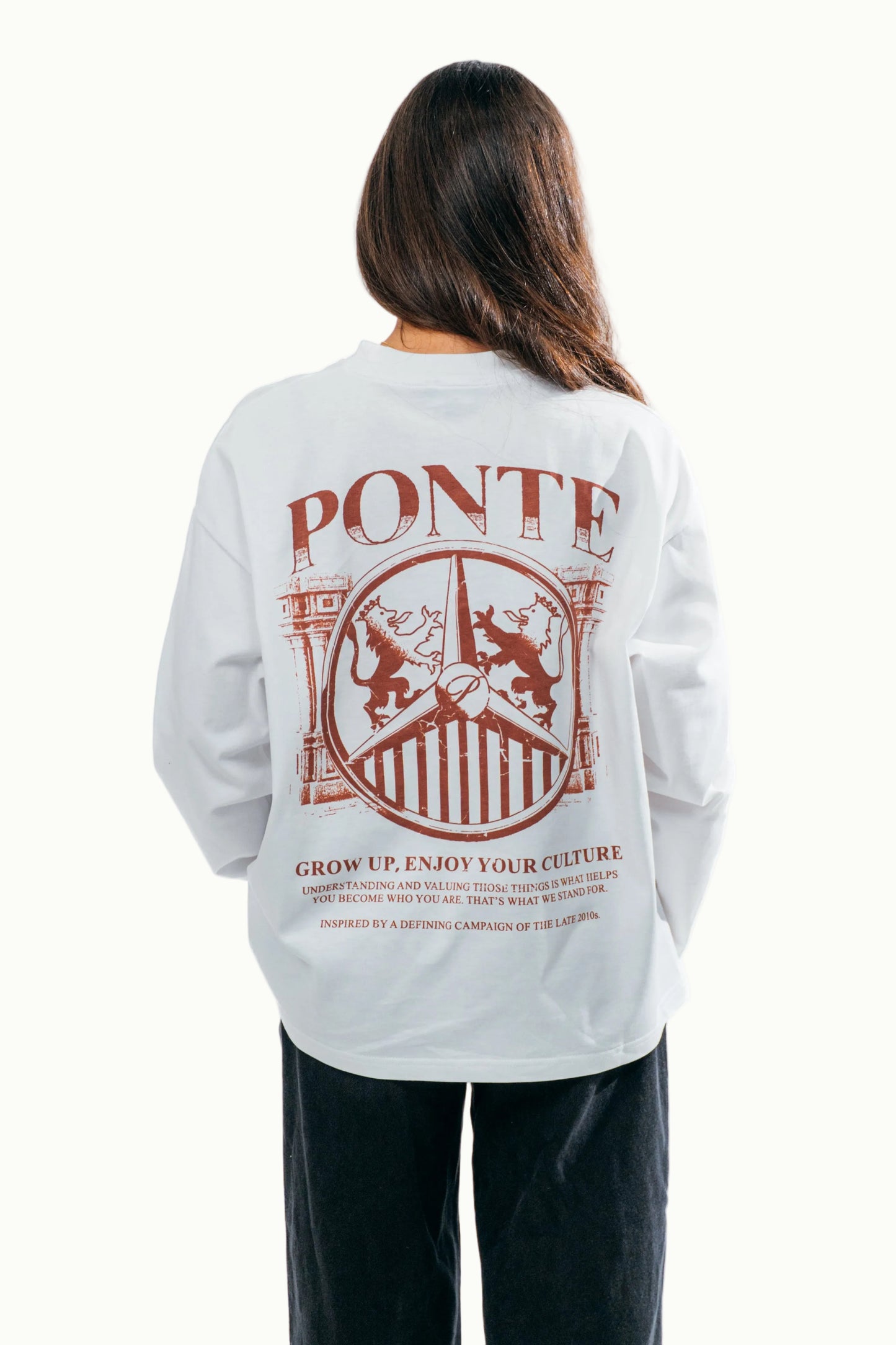 Modelo chica de espaldas con camiseta manga larga Our Culture blanca y estampado PONTE terracota con leones