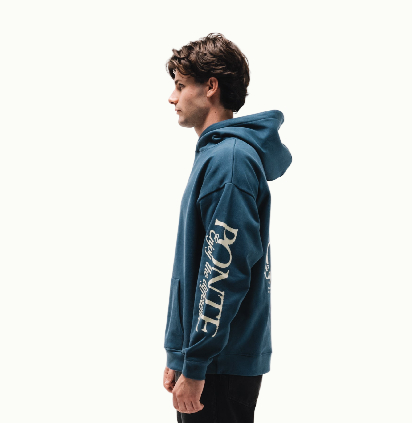 Modelo chico de perfil con sudadera Fly Different Hoodie azul petróleo y letras PONTE en manga
